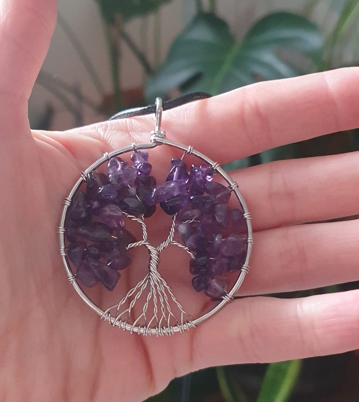 Amethyst tree of life pendant, its crystal chips wrapped in wire, held in an open hand